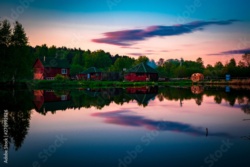 Small village red houses reflects in clearly still water at evening