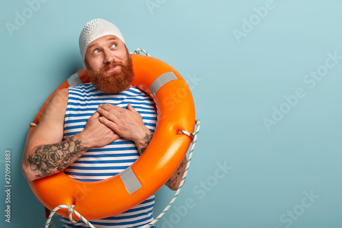 Pleased male swimmer makes gratitude gesture, feels thankful to lifegurads or swim instructor for professional lessons and staying safe, dreams learn swimming, wears special swimcap, uses lifebuoy