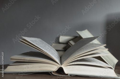 Old history book lying open on the wooden desk ready to be read and other books in the backround. © Radovan