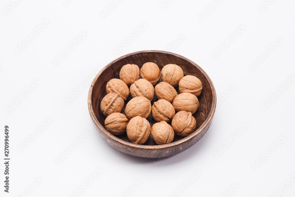 Wooden plate with walnuts isolated on white Wooden plate with walnuts isolated on white