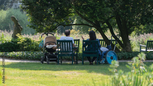 Familie mit Kinderwagen auf einer Bank im Park