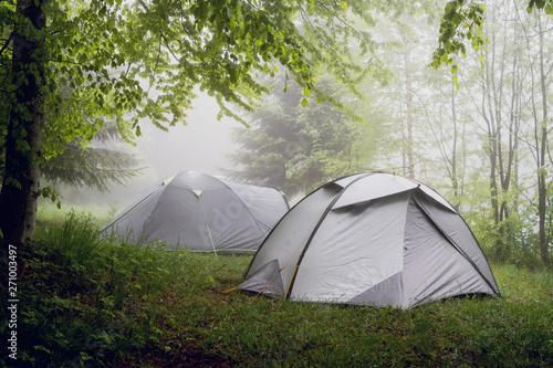 Camping in the nature, tents in the mountain range in a misty fog rainy day