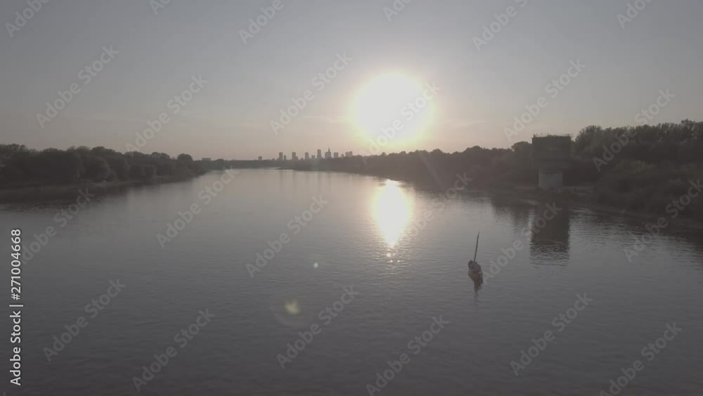 Aerial view of the pleasure boat with a sail sailing along the Vistula River towards the city of Warsaw at sunset. Filmed from 4K drone in RAW. Video for post-processing. Aerial view of the pleasure boat with a sail sailing along the Vistula River towards the city of Warsaw at sunset. Filmed from 4K drone in RAW. Video for post-processing.