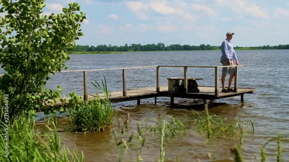 man stands on a pier at the lake in windy weather man stands on a pier at the lake in windy weather