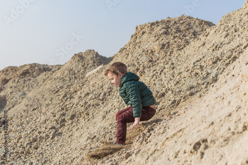 A little boy is climbing a sand mountain.