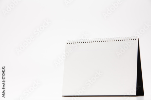 A white paper calendar stands on the table in photo