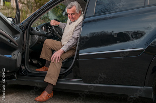 Senior man having  pain in hte knee while getting out of his car