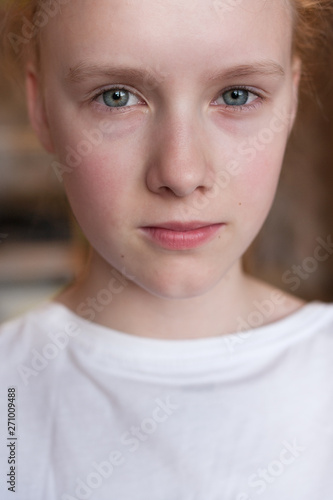 Cute Caucasian blond young girl angry frowns, studio portrait on brown background