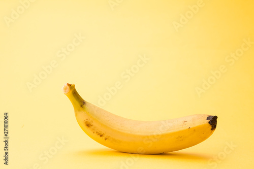 Single banana isolated on yellow background