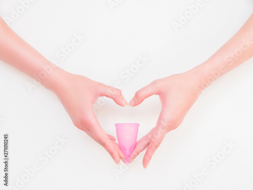 Close up of woman heart shaped hands holding menstrual cup isolated on white background. Eco-friendly concept for women's health. Innovation product in gynecology that replaced traditional approaches. photo