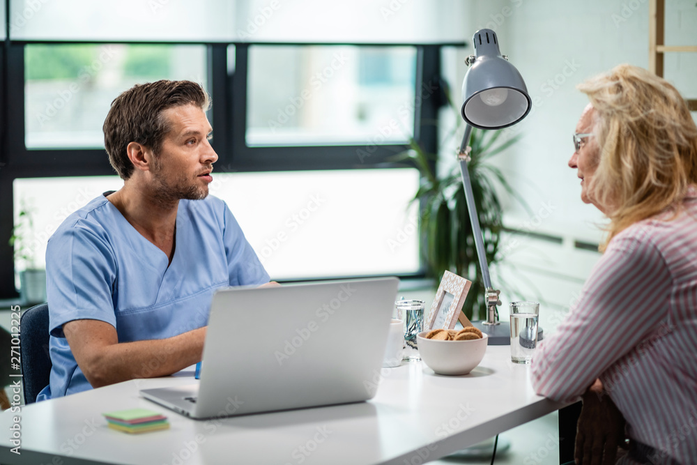 Fototapeta premium General practitioner talking to mature woman at doctor's office.