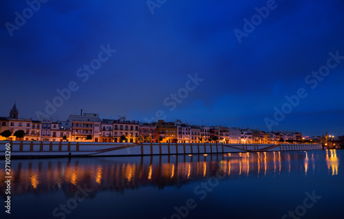 Houses on Betis street to Isabel bridge Seville reflected at dawn in Alfonso XIII Canal