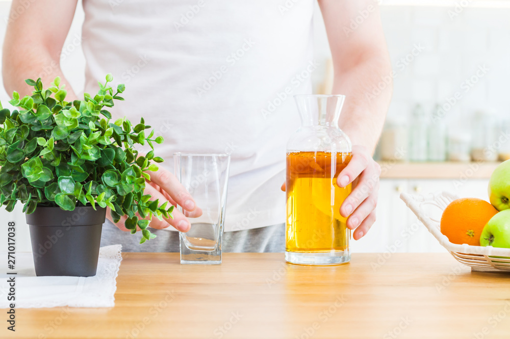 Man pouring apple juice from jug into an empty glass in the kitchen. Man pouring apple juice from jug into an empty glass in the kitchen.
