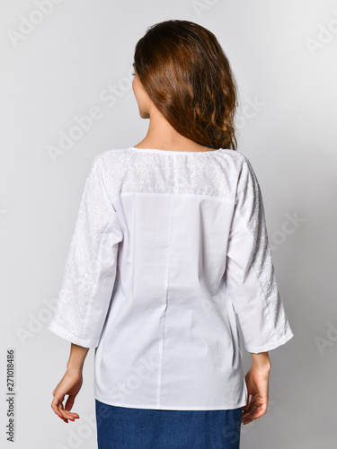 back of a young brunette girl with long hair in a white blouse and blue skirt. on a light background © FAB.1