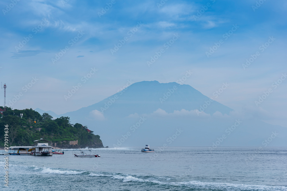 beautifull view on Bali from beach, early morning with fogs in front of Agung mount vulcano, blue sky background