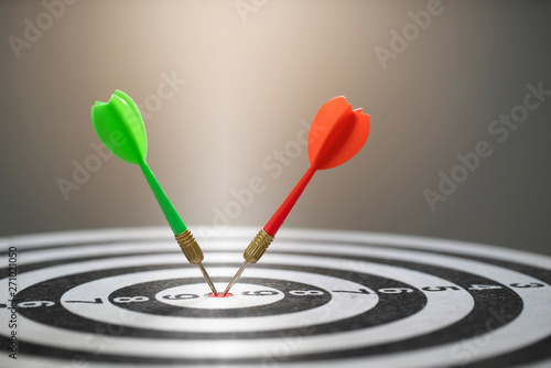 Close up red and green dart arrow hitting on target center of dartboard, business concept
