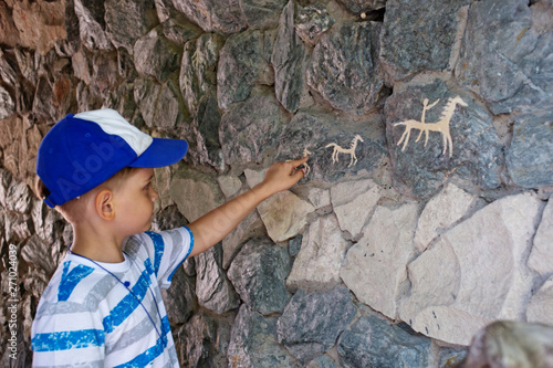 Fototapeta Naklejka Na Ścianę i Meble -  Ancient cave paintings and little boy. Bronze Age culture dated to the first half of the 2nd millennium BC.