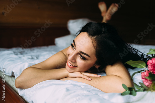 young beautiful girl is lying on the bed early in the morning and smiling cheerfully