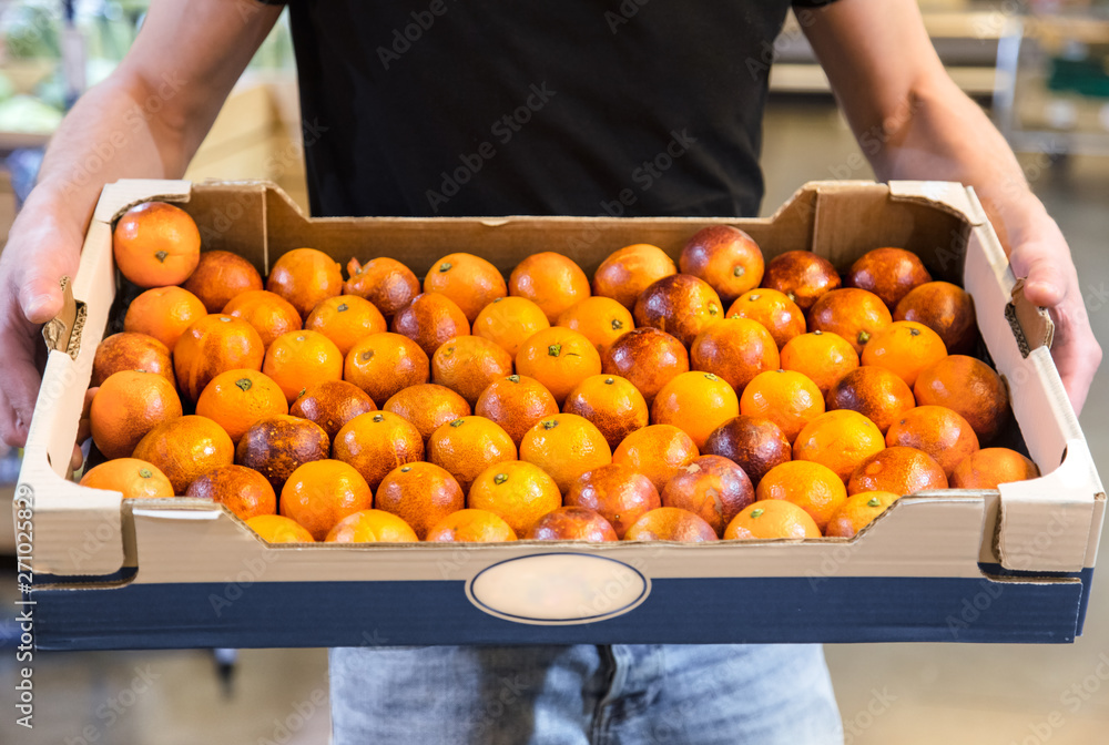 Smiling customers buying sicilian oranges in grocery section