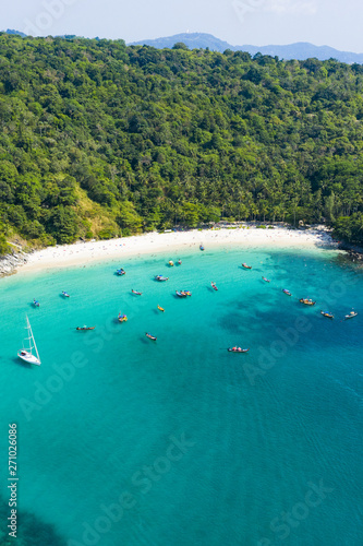 View from above, stunning aerial view of a beautiful tropical beach with white sand and turquoise clear water, long tail boats and people sunbathing, Freedom beach, Phuket, Thailand.