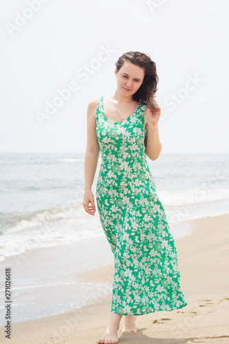 young girl with brown hair walks barefoot on the beach