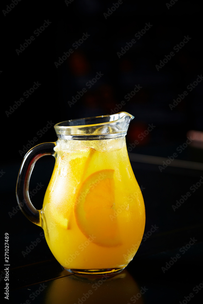 Orange juice in pitcher on black background Orange juice in pitcher on black background