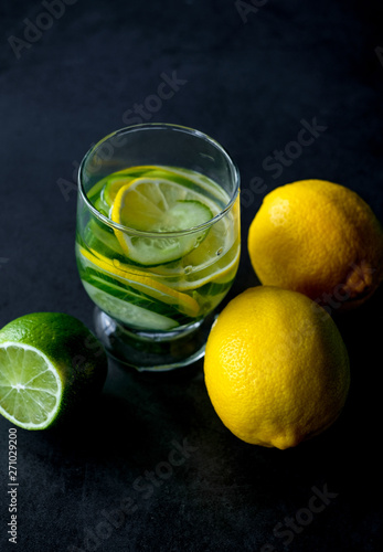 yellow lemon and lime, glass of water  on black background 