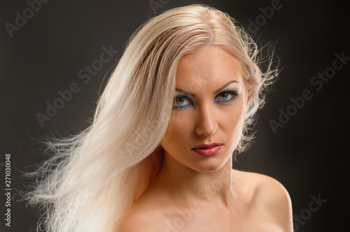 Young blonde woman with healthy straight hair showing shoulder