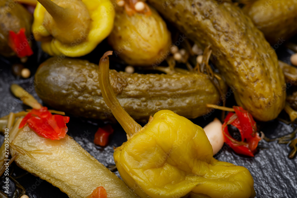 Cornichons (Mini French style Gherkin Cucumbers) and Pickled Pepperoncini Peppers on natural stone background. Cornichons (Mini French style Gherkin Cucumbers) and Pickled Pepperoncini Peppers on natural stone background.