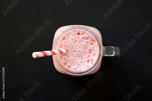 Strawberry banana smoothie in a glass jar mug, top view. Overhead, from above, flat lay.