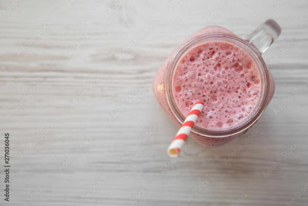 Strawberry banana smoothie in a glass jar mug over white wooden background, top view. Copy space. Strawberry banana smoothie in a glass jar mug over white wooden background, top view. Copy space.