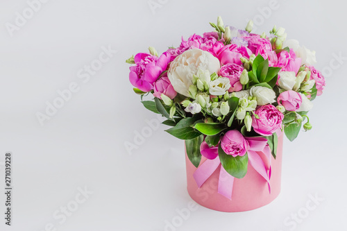 Arrangement of flowers in a hat box. Bouquet of peonies  eustoma  spray rose in a pink box with an oasis on a white background with copy space