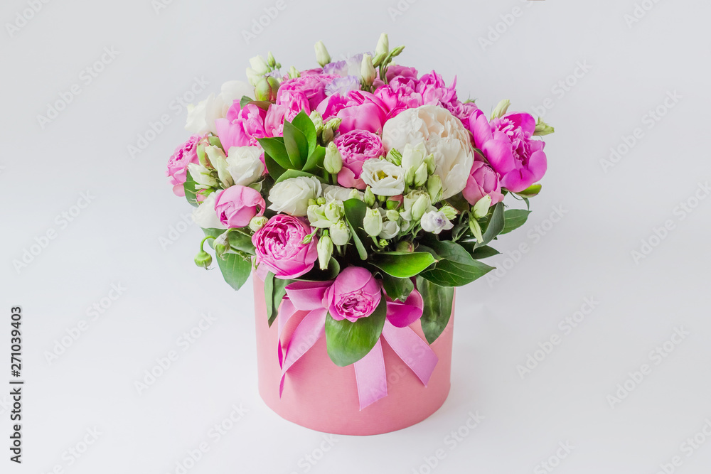 Arrangement of flowers in a hat box. Bouquet of peonies, eustoma, spray rose in a pink box with an oasis on a white background Arrangement of flowers in a hat box. Bouquet of peonies, eustoma, spray rose in a pink box with an oasis on a white background