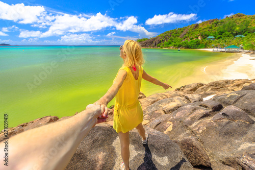 Tropical summer vacations. Follow me. Tourist woman in yellow holding hand of partner at Praslin in Seychelles.Aerial view of Anse Gouvernement with crystal waters and pristine beach near Anse Volbert photo