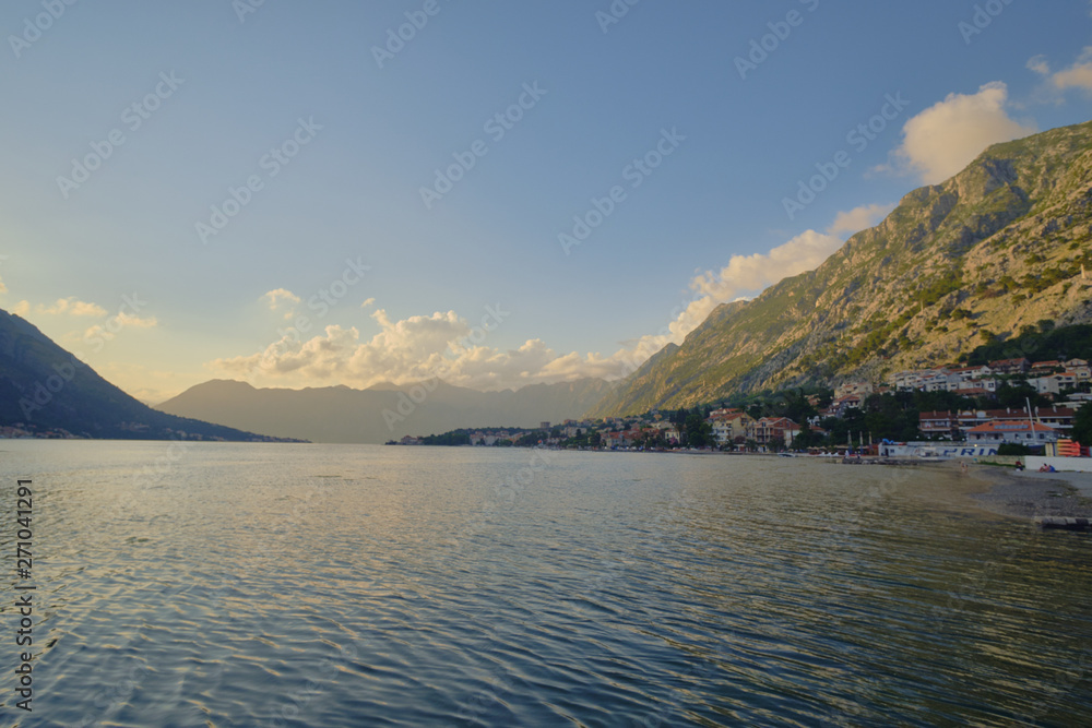 Boko Kotor bay at sunset, the clouds over the mountains, the sun at sunset leaving into the sunset.
