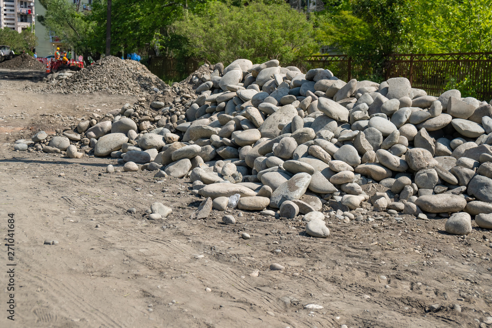 pile of rounded stones piled in the side of the road. stones for road. pile of rounded stones piled in the side of the road. stones for road.