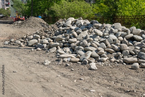 pile of rounded stones piled in the side of the road. stones for road.