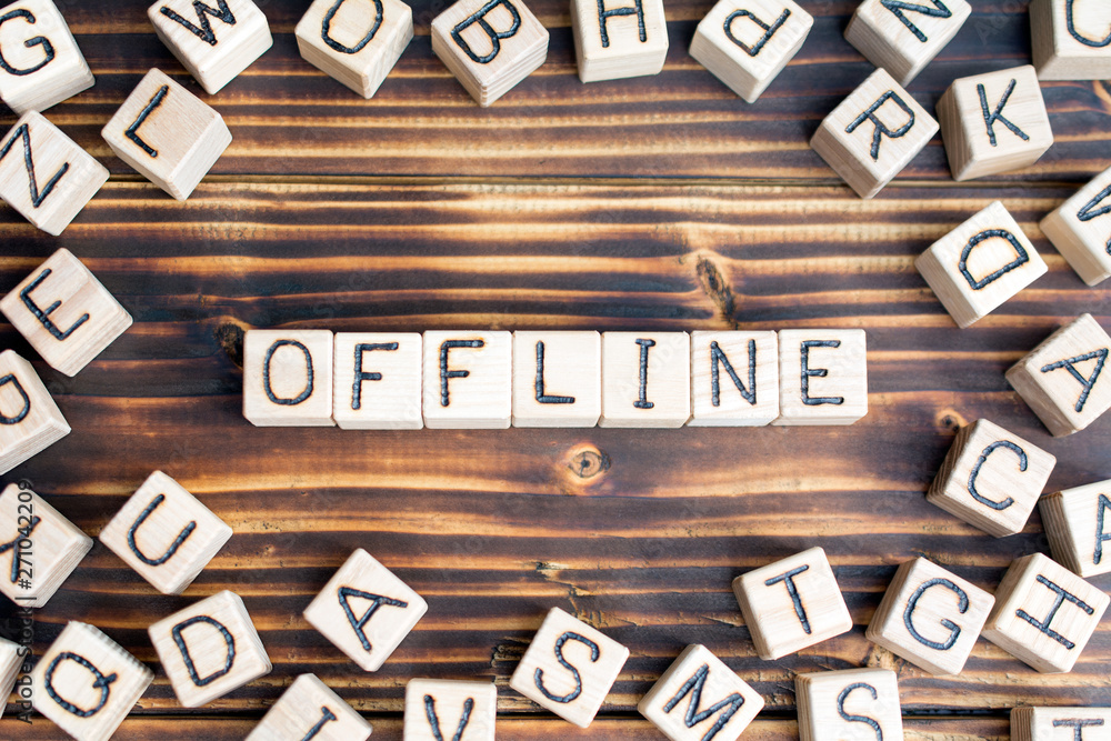 word offline wooden cubes letters, on a dark wooden burnt background, random letters are scattered around