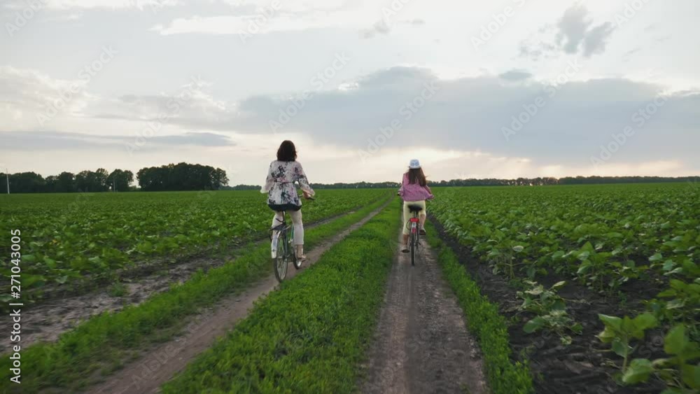 Mother with daughter on bicycles rides on a dirt road Mother with daughter on bicycles rides on a dirt road