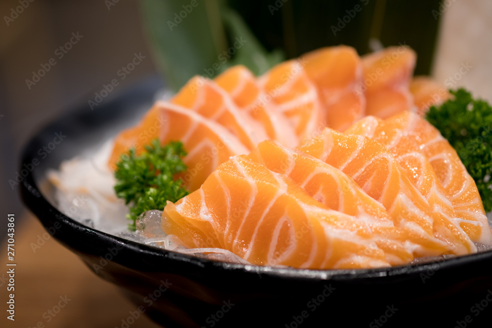 Raw salmon slice serve on ice in bowl.