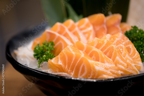 Raw salmon slice serve on ice in bowl.