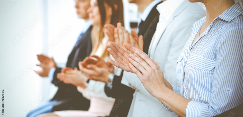 Obraz premium Business people clapping and applause at meeting or conference, close-up of hands. Group of unknown businessmen and women in modern white office. Success teamwork or corporate coaching concept