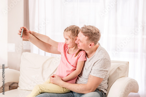 Father and kid are taking selfie in living room