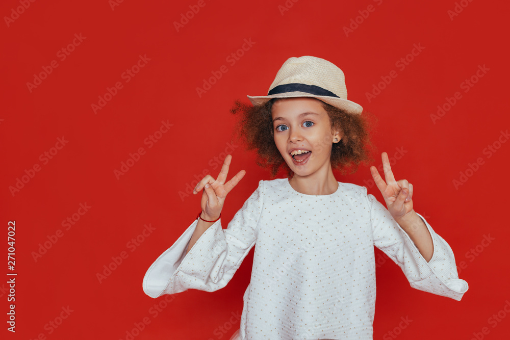 Headshot portrait of little girl with curly hair and blond hat, smiling, looking at camera Headshot portrait of little girl with curly hair and blond hat, smiling, looking at camera