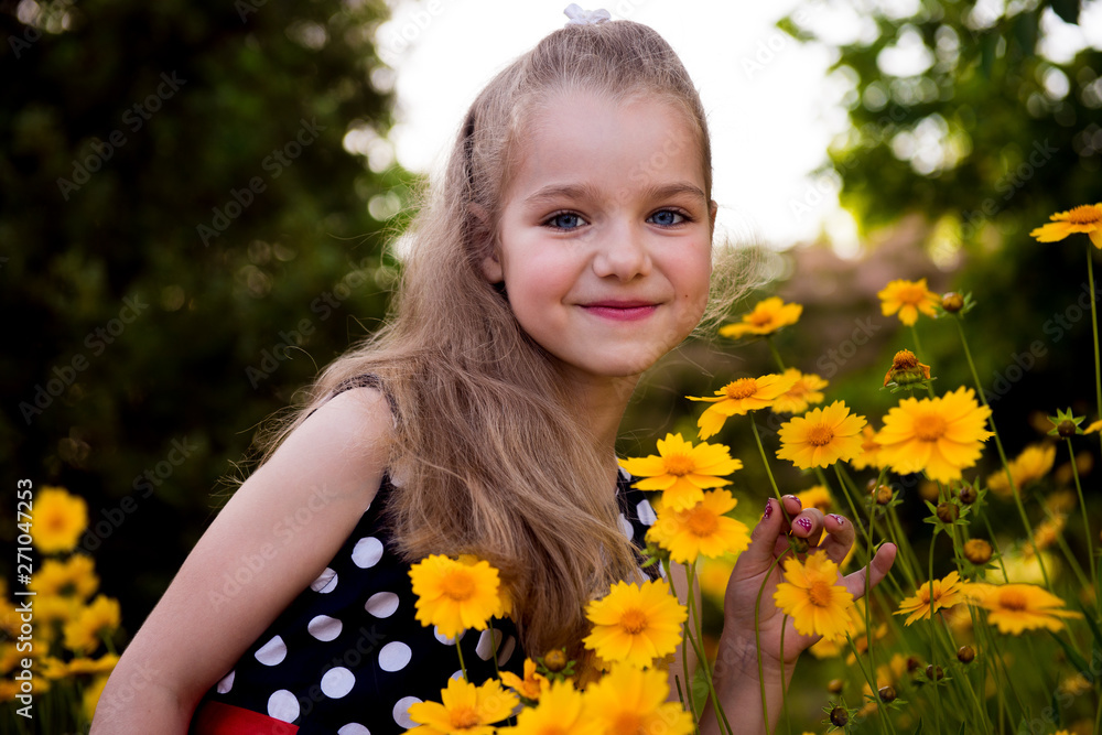 Portrait of a beautiful smiling girl outdoor. Summer portrait of a smiling girl. Little beautiful girl blonde in colors. Garden with yellow flowers, summer girl Portrait of a beautiful smiling girl outdoor. Summer portrait of a smiling girl. Little beautiful girl blonde in colors. Garden with yellow flowers, summer girl