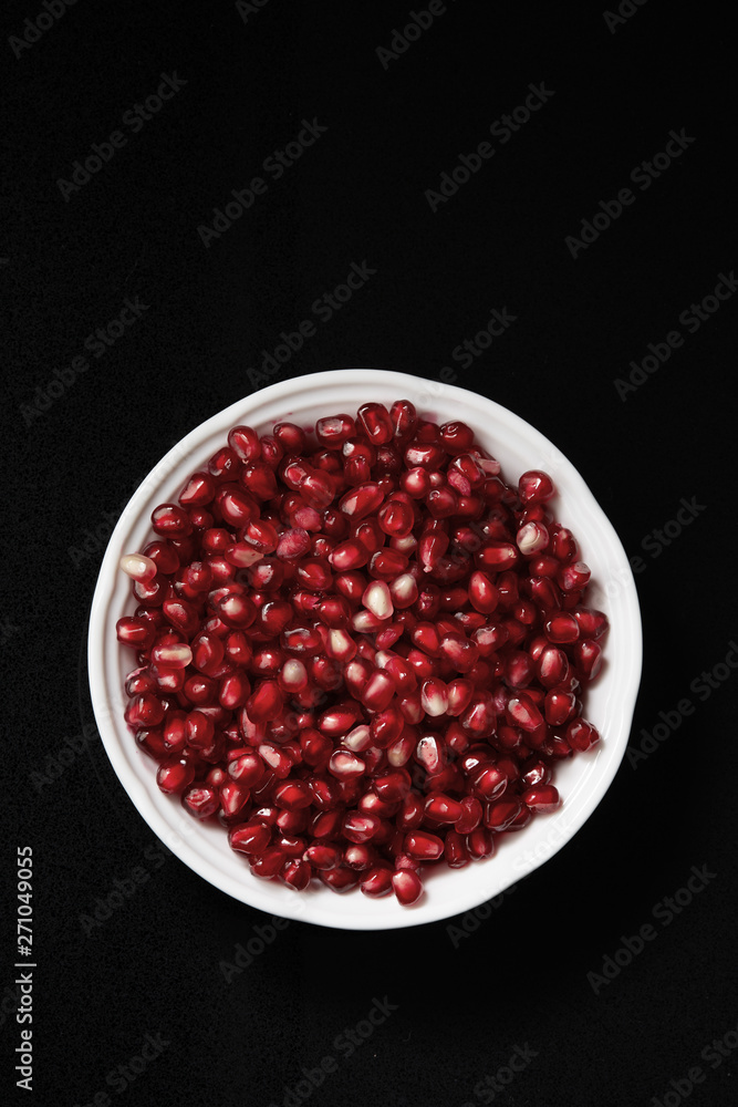 Pomegranate seeds in a bowl on a dark background. Top view Pomegranate seeds in a bowl on a dark background. Top view