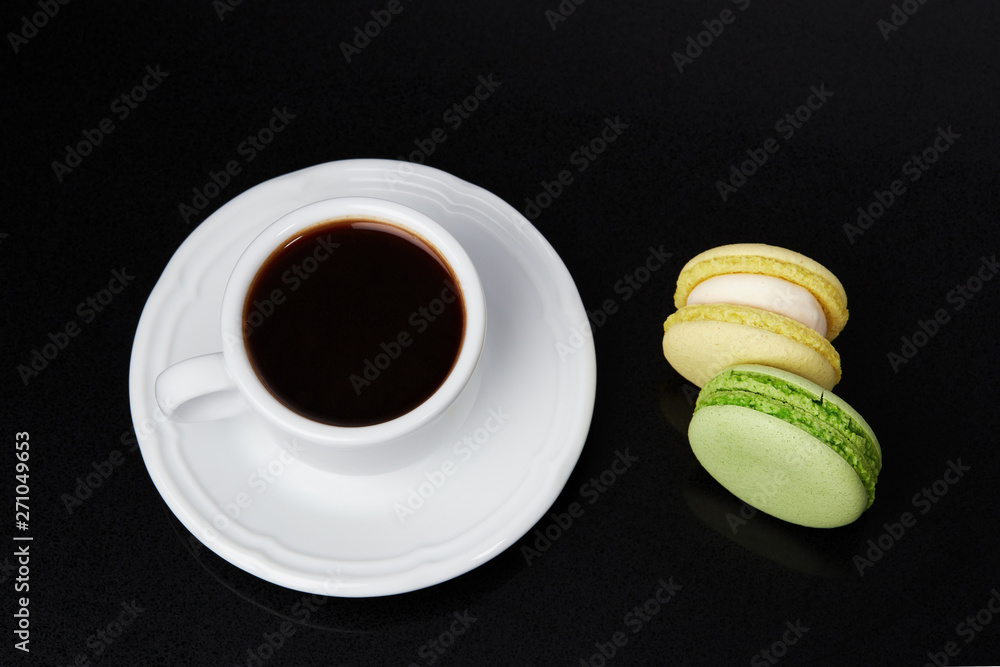 Cup of espresso and macaroons on a black background. Top view
