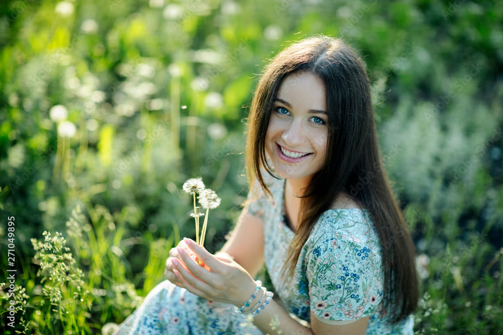 woman with a dandelion in the lush spring meadow in the rays of the setting sun woman with a dandelion in the lush spring meadow in the rays of the setting sun