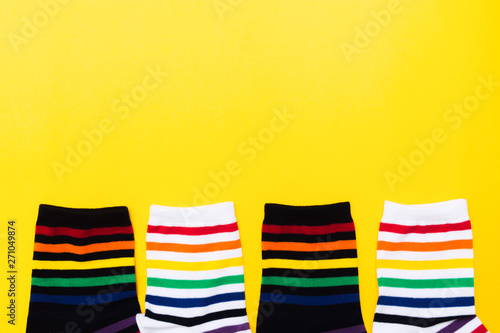 Four black and white socks with colorful striped background over yellow background photo
