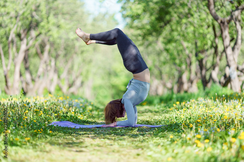 Image of woman standing on hands doing yoga in forest